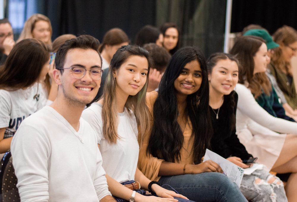 Smiling students sit in the crowd