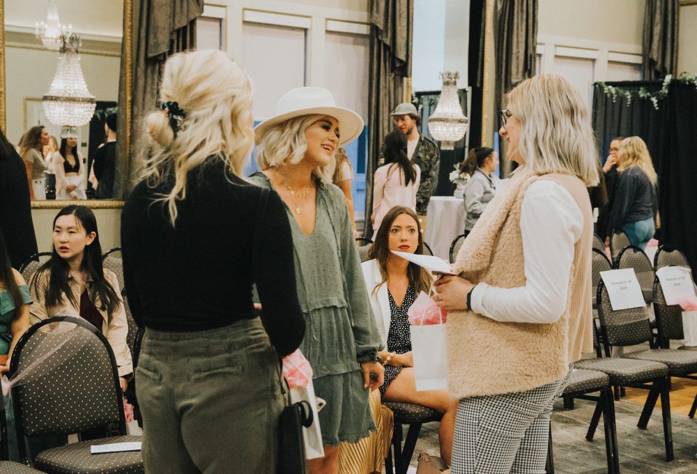 A group of people stand talking and smiling