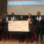 Adam White collects his oversized check in a group photo.