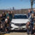 Students pose in front of the Acura car with the City of Pittsburgh in the background